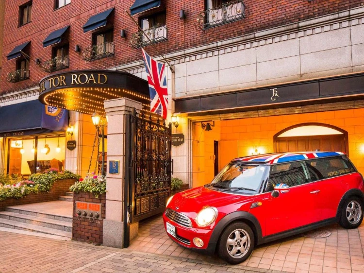 酒店的正門，裝飾著英國國旗和紅色 Mini Cooper 汽車，帶有典雅的歐洲風格。